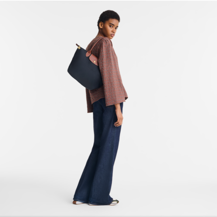 Person holding a navy blue tote bag on a white background- black purse