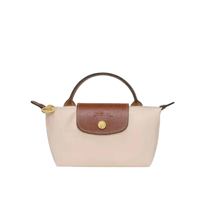 A small structured handbag with a pale beige body, brown leather top handle and front flap, and gold-tone hardware, shown on a plain light gray background.