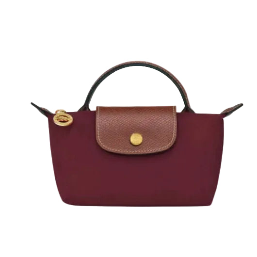A structured top-handle handbag in deep burgundy with a brown textured flap and gold-tone hardware, shown against a plain white background.