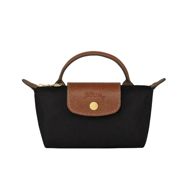 A black canvas handbag with a brown leather top handle, flap, and gold-tone hardware, shown against a plain light gray background.