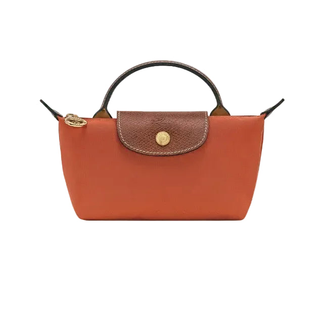 A brick leather handbag with a brown textured flap, gold-tone hardware, and a top handle, shown against a light gray background.